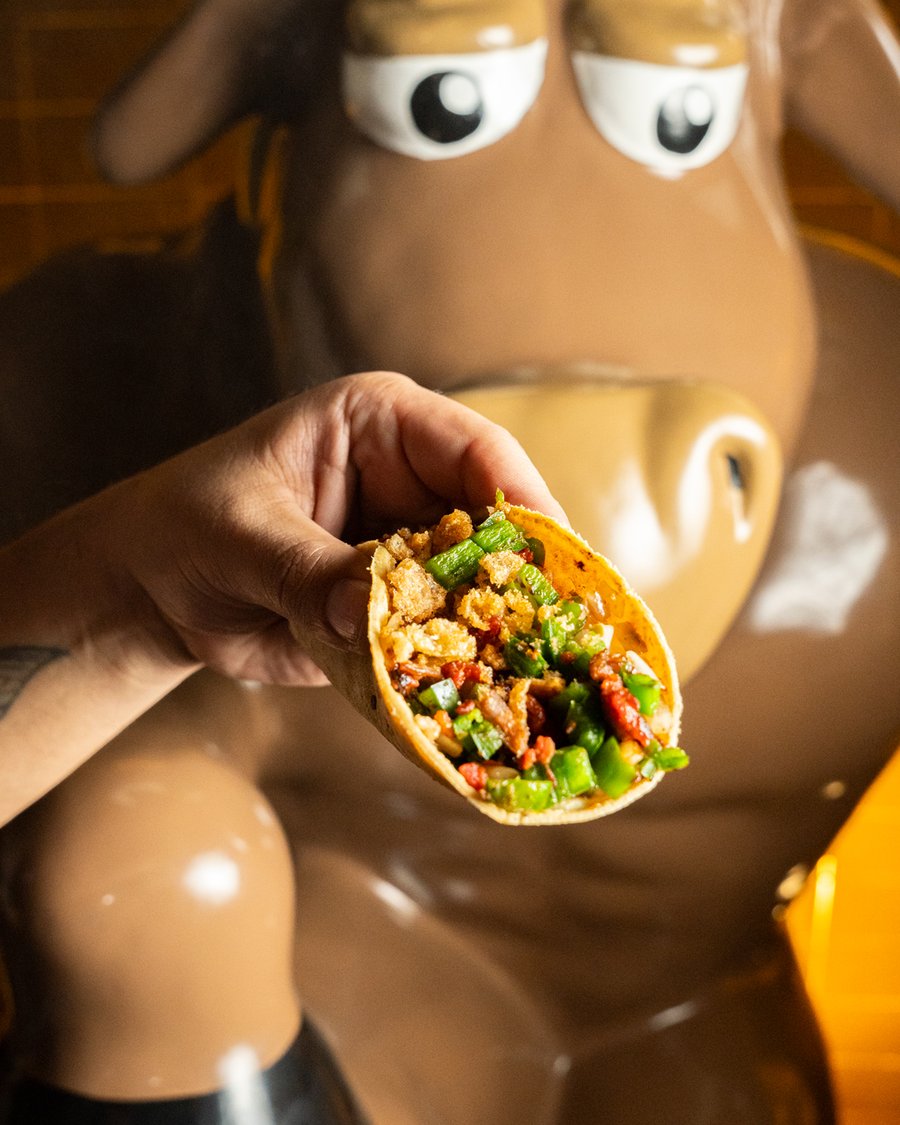 Comensal disfrutando un taco campechano junto al toro Don Manolito
